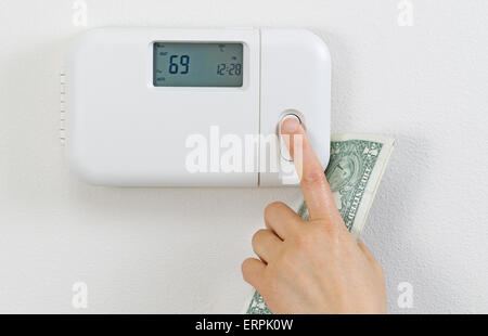 Nahaufnahme des weiblichen Hand einstellen Heizungsthermostat mit teilweise Währung Geld in Palm. Stockfoto