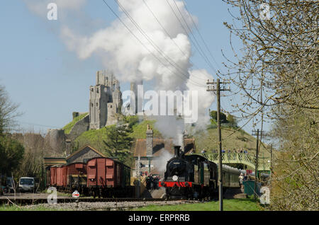 Verlassen Sie den Bahnhof am Corfe Dampfzug. Corfe Castle im Hintergrund. Dorset, UK. April. Stockfoto