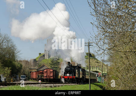 Verlassen Sie den Bahnhof am Corfe Dampfzug. Corfe Castle im Hintergrund. Dorset, UK. April. Stockfoto