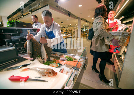 Ein Fischhändler an seiner Theke halten Scholle und Wolfsbarsch mit ein Knurrhahn (Vordergrund) UK Stockfoto