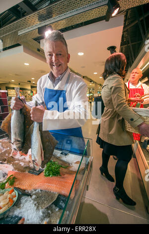 Ein Fischhändler an seiner Theke halten Scholle und Wolfsbarsch UK Stockfoto