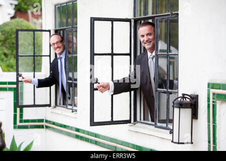 zwei Geschäftsleute aus dem Fenster schauen und Lächeln Stockfoto