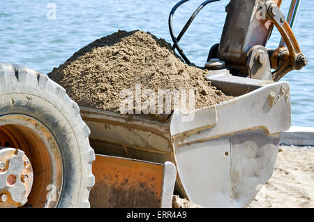 Nahaufnahme von der Schaufel voll Sand in der Nähe des Sees ein Bagger Stockfoto