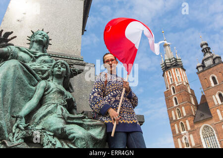 Junge Frau mit der Flagge der Republik Polen auf das Quadrat von Krakau, Marienkirche im Hintergrund. Stockfoto