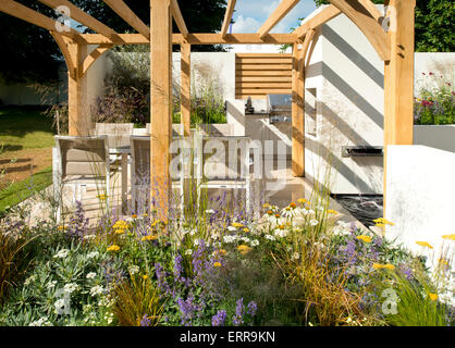 Ein Esstisch mit Stühlen in einer Außenküche unter einer Pergola in der Al-Fresco-Garten von The Hampton Court Flower Show, 2014 Stockfoto