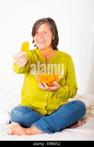 Frau im Bett mit Kartoffel-Chips bietet einen chip Stockfoto