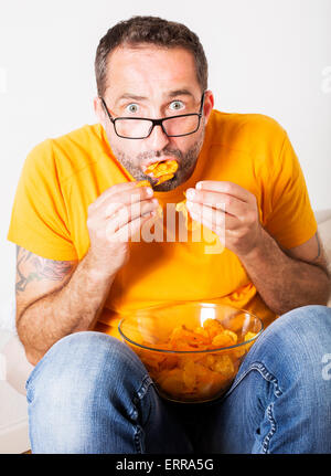 Mann mit Brille sitzen und Essen Kartoffelchips Stockfoto