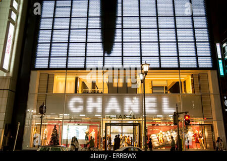 Das Parfümgeschäft Chanel in der Ginza, Tokio. Abend, Außenansicht des Gebäudes mit Menschen, die an Fenstervorzeigen vorbeigehen, und Eingang, Stockfoto