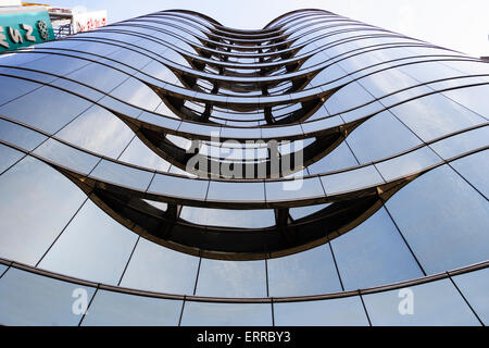 Tokio. Der niedrige Blickwinkel blickt gerade nach oben auf die Fassade eines elfstöckigen, geschwungenen, dunkelglasierten Büroblocks. Stockfoto