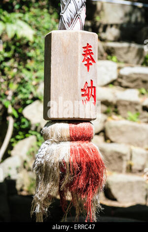 Goscha-Inari-Schrein in Kobe, Japan. Hanfglockenseil mit Holzgreifer mit roter Kanji-Zeicheninschrift aufgemalt. Stockfoto