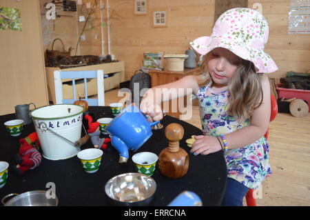 Ein vier Jahres altes Mädchen spielt mit einem Tee-Set in einer Holzhütte. Vivienne Johnson/Alamy Live-Nachrichten Stockfoto