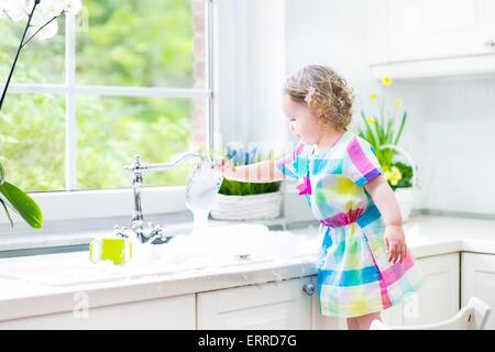 Kind abwaschen. Kinder waschen Teller und Tassen. Kleines Mädchen