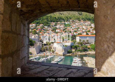 Blick durch die Fenster in der dicken Dubrovnik Stadtmauer, Gestaltung, den malerischen Hafen und äußeren Stadtgebäude Stockfoto