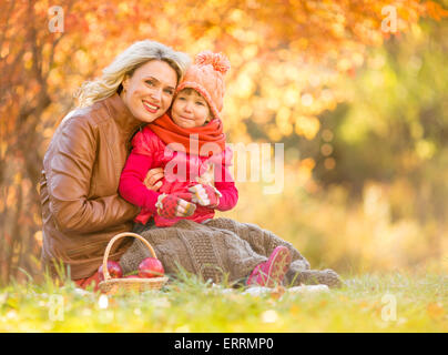 Glückliche Mutter und Kind sitzt im Freien im Herbst Stockfoto