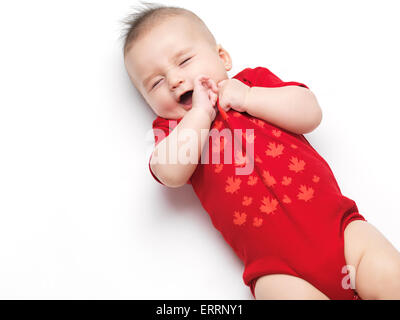 Glücklich niedlich gähnende vier Monate altes Baby junge rote Körper Anzug. Isoliert auf weißem Hintergrund. Stockfoto