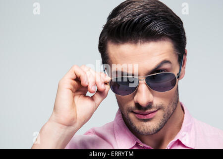 Closeup Portrait eines jungen Mannes der Mode Sonnenbrillen Blick in die Kamera über den grauen Hintergrund Stockfoto