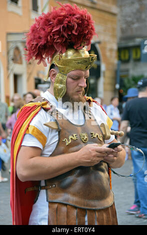 Ein Straßenmusikant verkleidet als Gladiator in der Nähe des Pantheon in Rom seine e-Mail auf einem Handy überprüft. Stockfoto