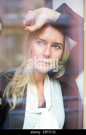 blonde Frau aus dem Fenster schauen Stockfoto