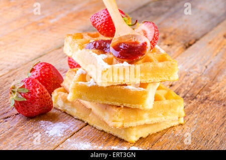 hausgemachte Waffeln mit Ahornsirup Erdbeeren auf hölzernen Hintergrund Stockfoto