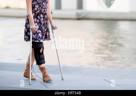 Nahaufnahme von Frau in einem Kleid gehen mit Krücken Stockfoto