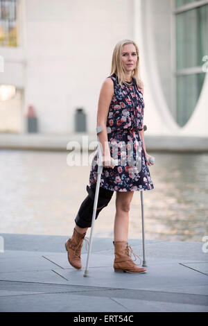 blonde Frau in einem Kleid gehen mit Krücken Stockfoto