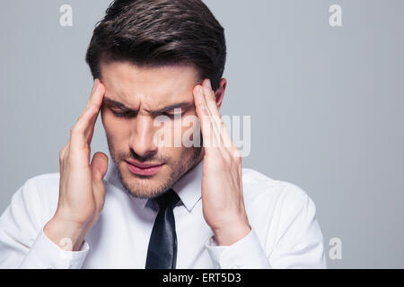 Geschäftsmann, Kopfschmerzen über grauen Hintergrund Stockfoto