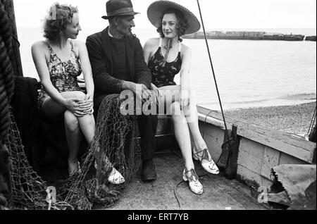 Frauen in ihren sitzen in einem Fischerboot mit einem Fischer an der Küste, Hastings, ca. 1945 Baden-Kostümen. Stockfoto