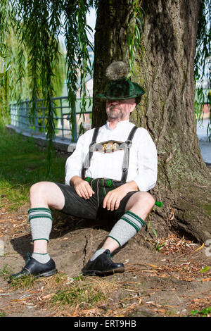 Mann in bayerischer Tracht von einem Baum sitzen und schlafen Stockfoto