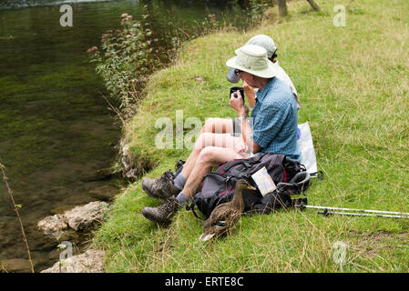 Mann und Frau saß am River bank Lathkill Dale National Nature Reserve in der Peak District Nationalpark Derbyshire Stockfoto