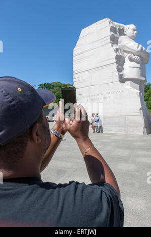 Ein afrikanisch-amerikanischer Mann nutzt eine Smartphone, um ein Foto von Martin Luther King Memorial in Washington, DC zu schnappen. Stockfoto