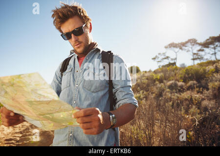 Schuss ein hübscher Wanderer mit Hilfe einer Karte. Wanderer mit Hilfe einer Karte um seiner Wanderung an einem Sommertag zu navigieren. Stockfoto