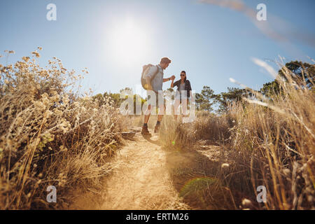 Im Freien Schuss des jungen Paares auf Wanderung zu Fuß auf Schmutz trail in Bergen, die Hand in Hand. Junger Mann und Frau Wanderer auf sunn Stockfoto