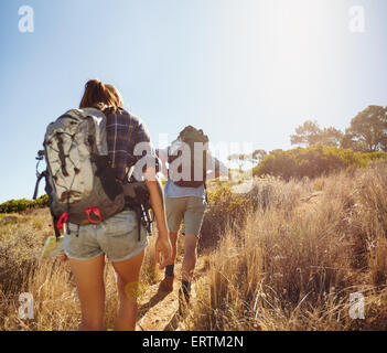 Rear-View-Bild von zwei jungen Menschen tragen Rucksäcke Wandern durch Berg hinauf zum Sommertag. Mann und Frau Wandern auf bri Stockfoto