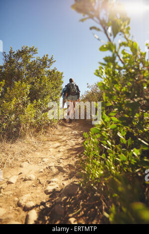 Bild von Menschen zu Fuß durch Bergweg. Rückansicht Schuss des Paares Wandern auf unbefestigten Weg durch Rasen und Pflanzen auf mountai Stockfoto