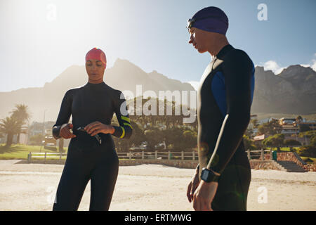 Aufnahme des jungen Mann und Frau mit ihren Badesachen im stehen am Strand. Triathleten, die Vorbereitung für das Rennen. Stockfoto