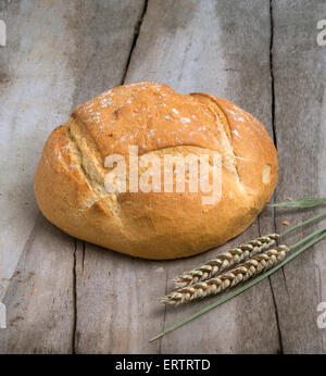 Laib Weißbrot auf einem alten Tisch mit Ähre Stockfoto