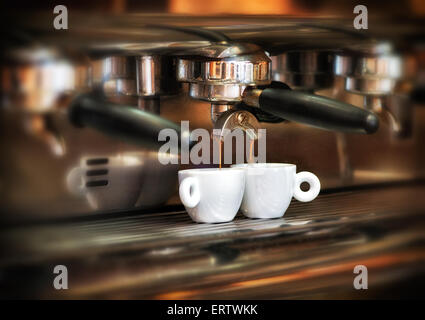 Italienische Espresso-Maschine auf einen Zähler in einem Restaurant Abgabe frisch gebrauten Kaffee in zwei kleine Tassen Stockfoto