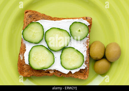 drei Oliven und gebratenen Toast mit Käse und Gurken Scheiben auf Teller grün Stockfoto