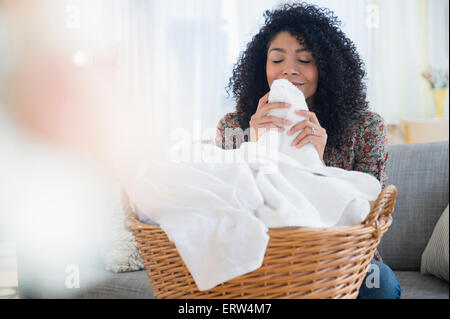 Gemischte Rassen Frau riechen saubere Handtücher in Wäscherei Stockfoto