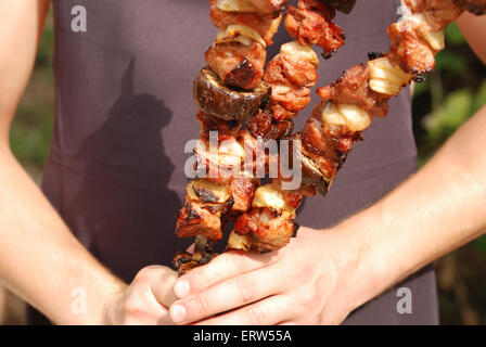 Der Koch hält zubereitete Fleisch und Gemüse in einer hand Stockfoto