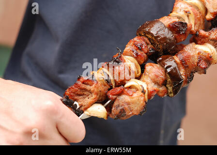 Der Koch hält zubereitete Fleisch und Gemüse in einer hand Stockfoto