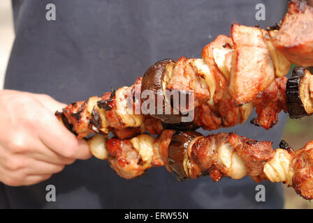 Der Koch hält zubereitete Fleisch und Gemüse in einer hand Stockfoto