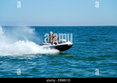 Mann auf einem hohen Geschwindigkeit Jetski mit Wasserspray Stockfoto