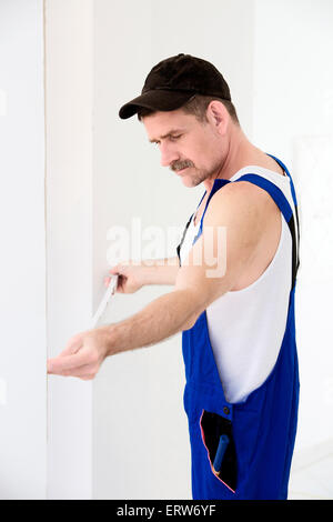 Handwerker, halten ein Maßband an der Wand Stockfoto