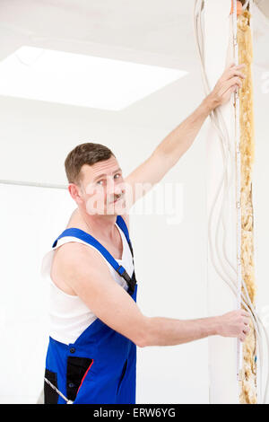 Handwerker, halten ein Maßband an der Wand Stockfoto