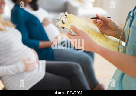 Krankenschwester Kennzeichnung medizinischen Diagramm in der Nähe von schwangeren Frauen Stockfoto