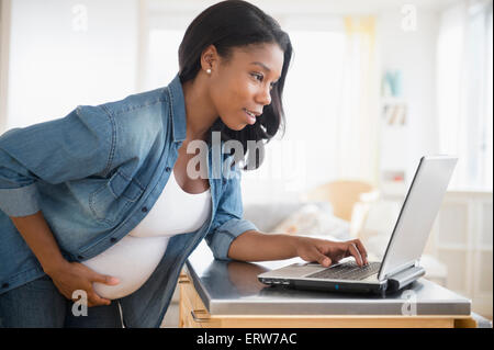 Schwarze schwangere Frau mit Laptop in der Küche Stockfoto
