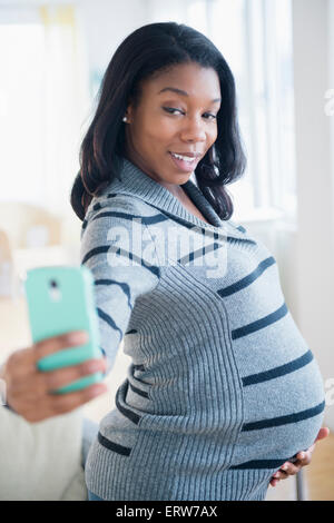 Schwarze schwangere Frau unter Handy selfie Stockfoto