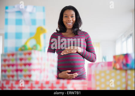 Schwarze schwangere Frau bewundern Geschenke an Baby-Dusche Stockfoto