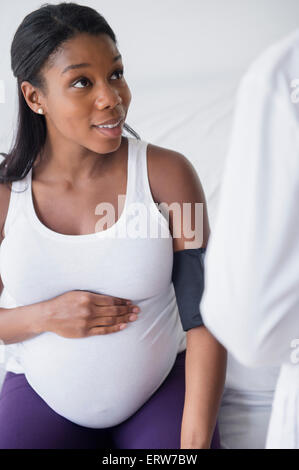 Arzt überprüft Blutdruck schwarze schwangere Frau Stockfoto